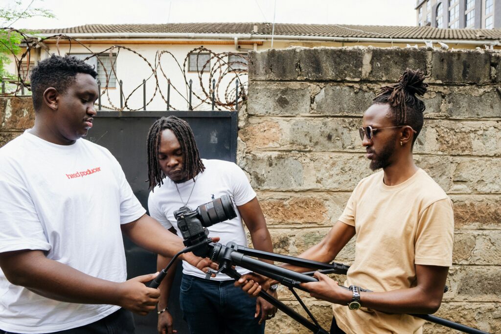 A three-person film crew setting up a camera on a tripod in Nairobi