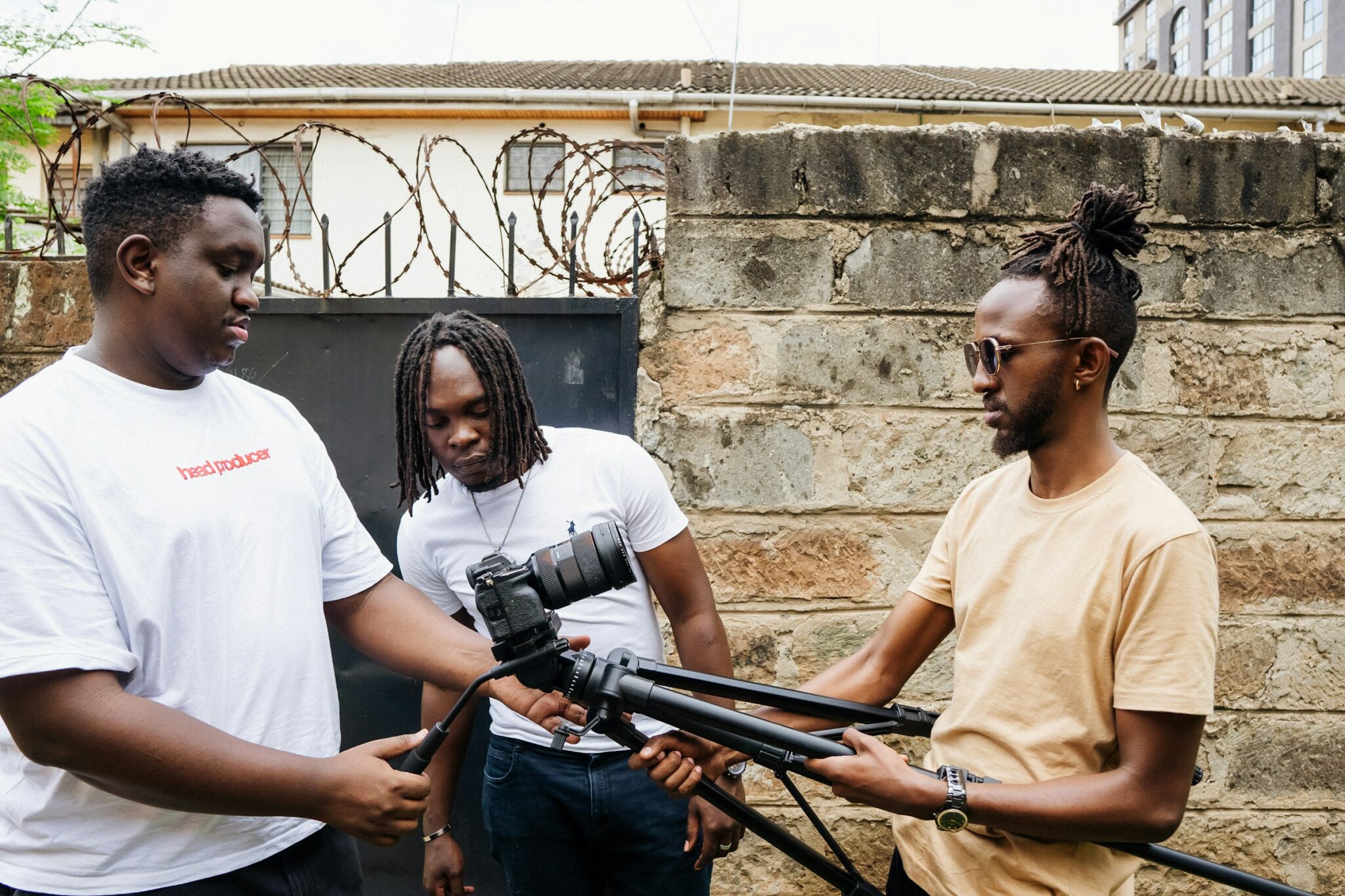 A three-person film crew setting up a camera on a tripod in Nairobi