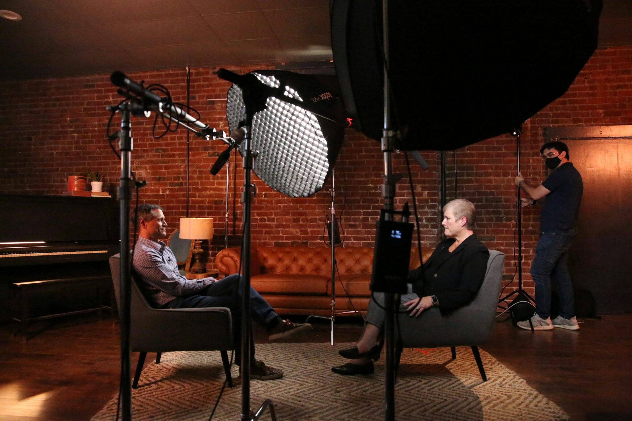 Two people seated for a filmed interview under studio lighting