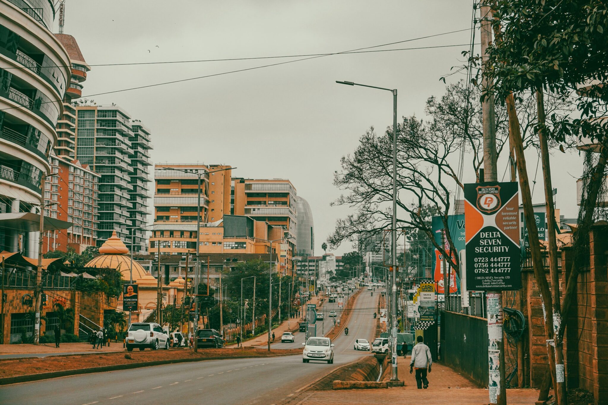 A pedestrian walks along a tree-lined street past high-rise buildings in Westlands, Nairobi