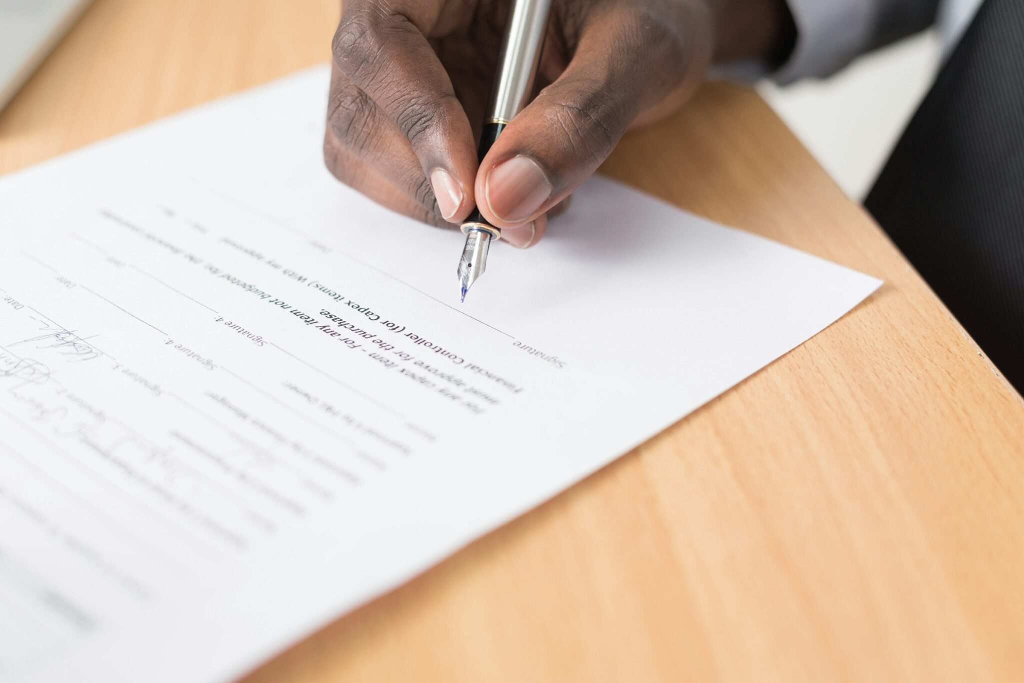 A hand holding a pen over a printed document on a desk in Nairobi, Kenya