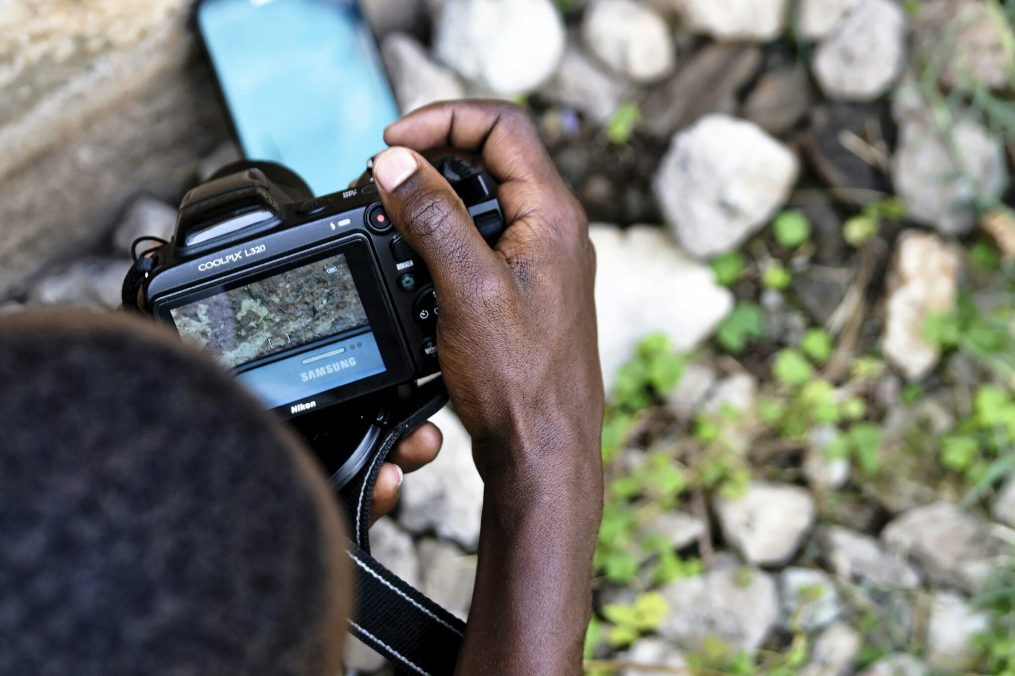 Over-the-shoulder view of a photographer in Nairobi reviewing a shot on the screen of a borrowed DSLR camera