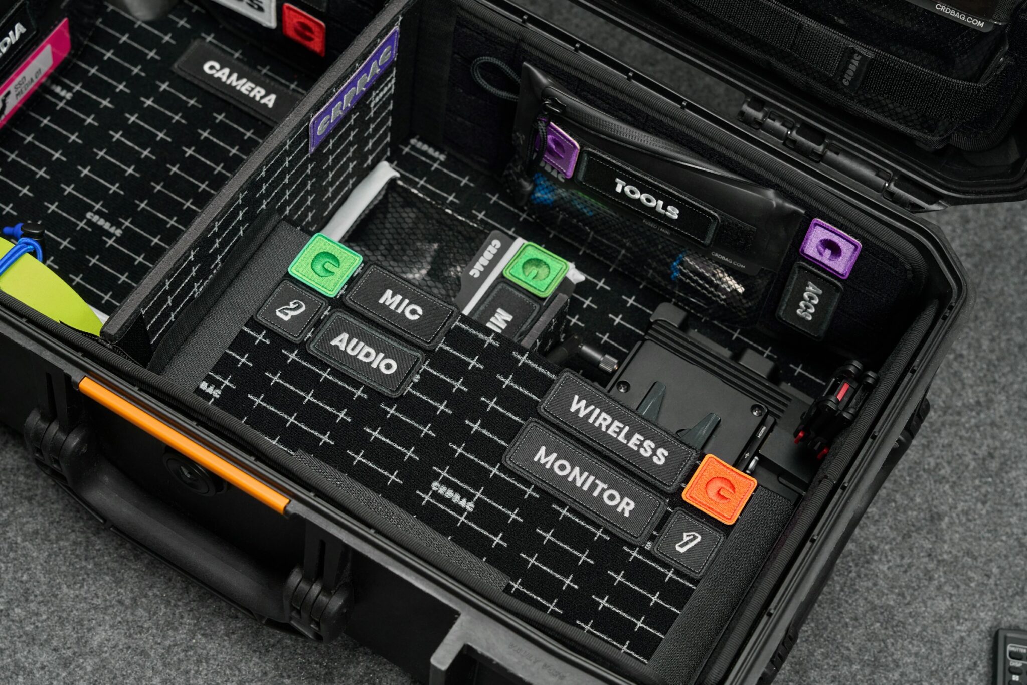 An open hard equipment case with labelled foam compartments for camera, microphones, audio, wireless and monitor kit