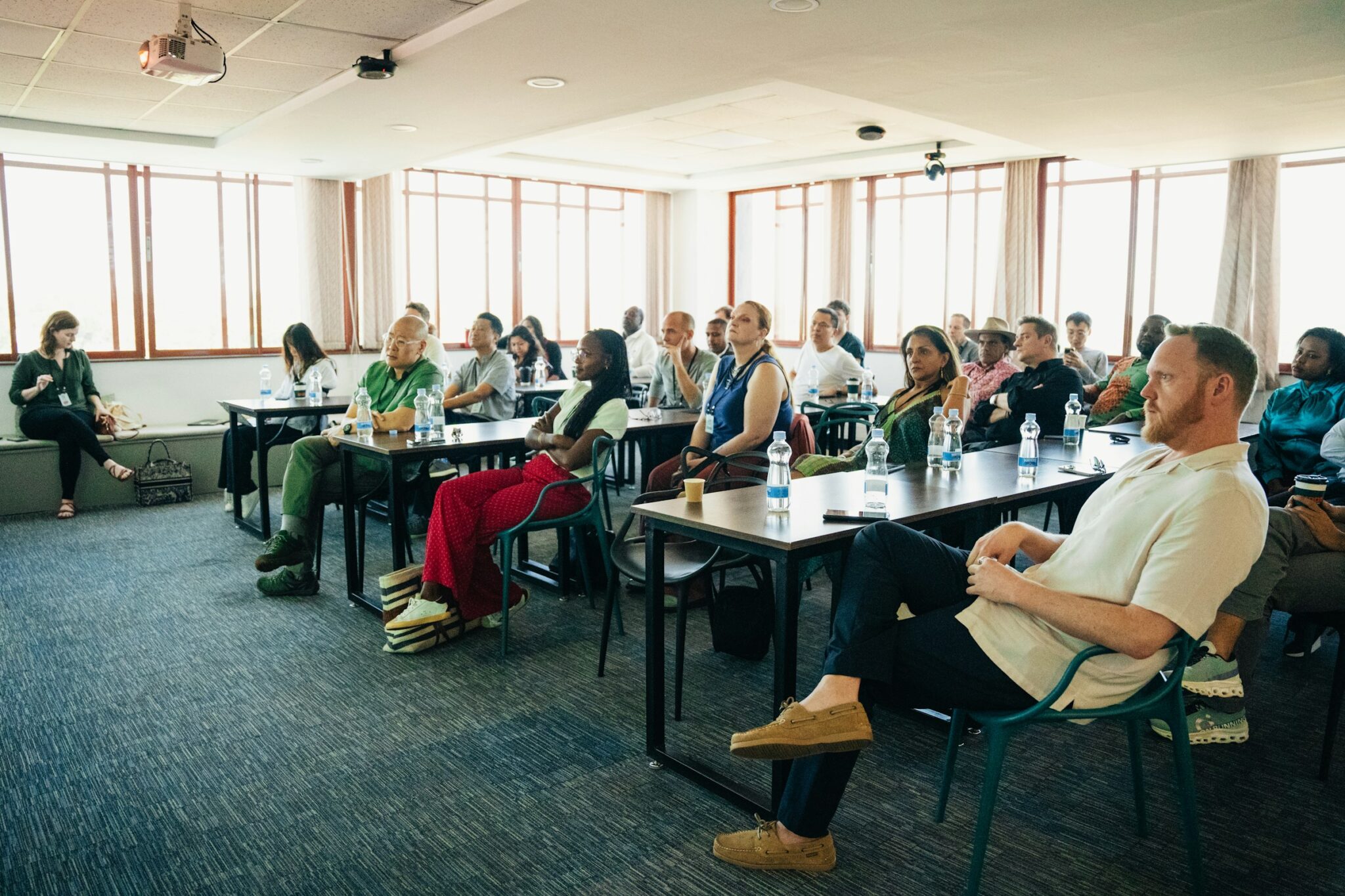 Delegates seated at tables in a bright conference room in Nairobi, Kenya, listening to a presentation