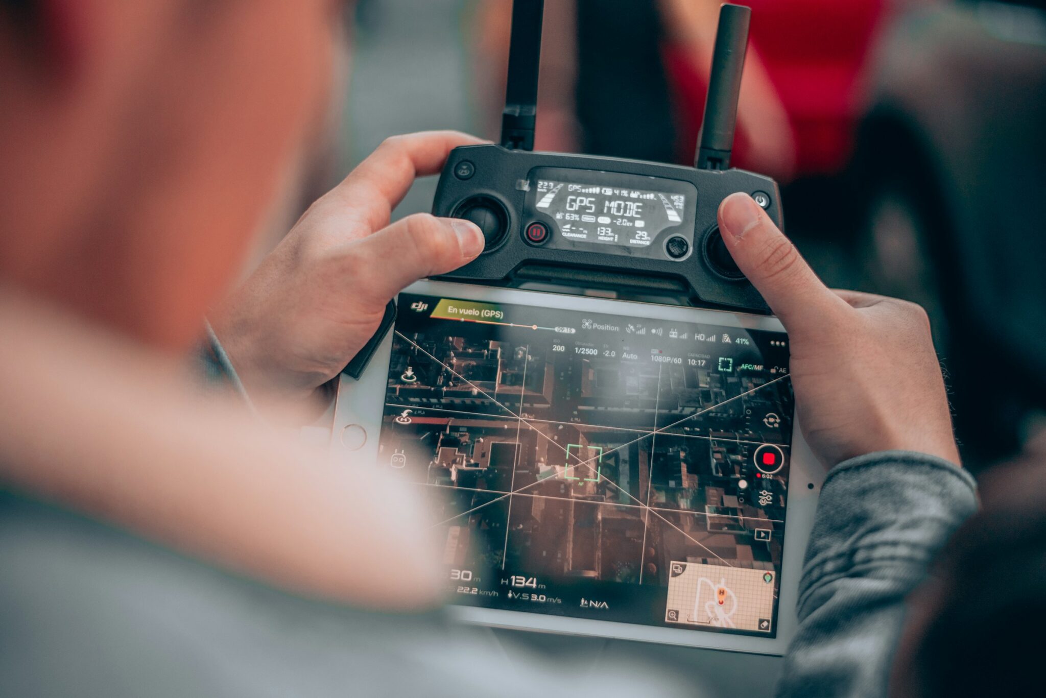 A drone operator holding a remote controller with a live camera view