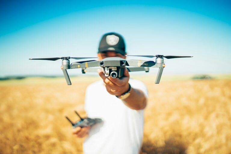 A drone pilot holding up a quadcopter in an open field